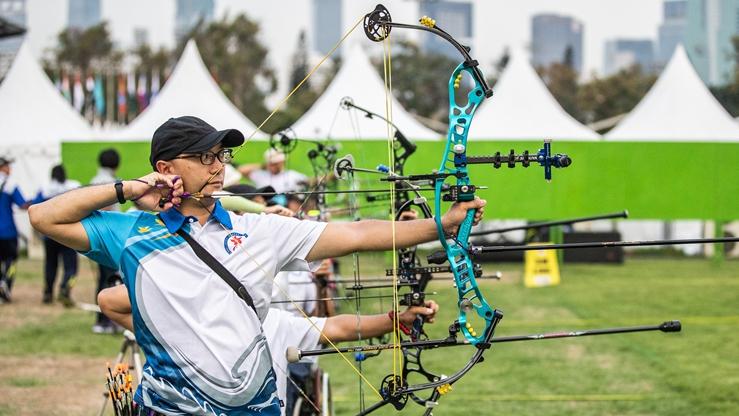 一位男運動員在戶外射箭比賽中拉弓瞄準